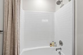 Brook Park apartment for rent - A white tiled bathroom with a shower and a white bathtub.