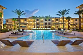 Spring apartment for rent - a large swimming pool with chairs in front of an apartment building