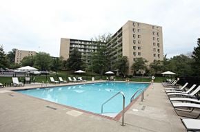 Mayfield Heights apartment for rent - A large swimming pool surrounded by lounge chairs and umbrellas in front of a large building.