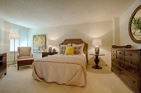 Mayfield Heights apartment for rent - A bedroom with a large bed, a chair, and a painting on the wall.