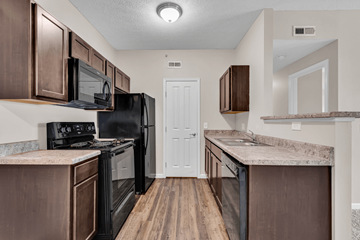 Reynoldsburg apartment for rent - A kitchen with brown cabinets and a black refrigerator.