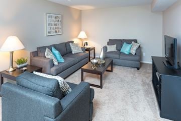 Copley apartment for rent - A living room with grey couches and a television.