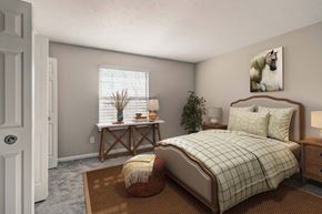 Westlake apartment for rent - A bedroom with a bed, a bench, and a potted plant.