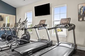 Brook Park apartment for rent - a gym with cardio machines and a tv on the wall
