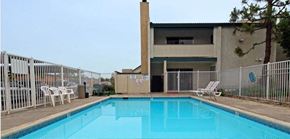 Bakersfield apartment for rent - a swimming pool in front of a building with a fence