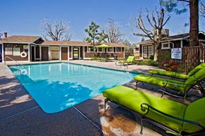 Bakersfield apartment for rent - a swimming pool with green chairs around it