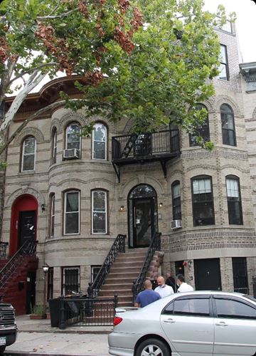 Brooklyn apartment for rent - A silver car is parked on the street in front of a building with a red door.