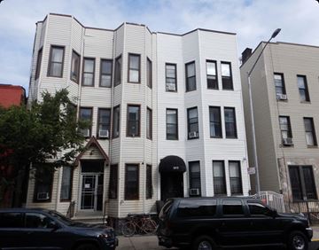 Brooklyn apartment for rent - A black SUV is parked in front of a white building.