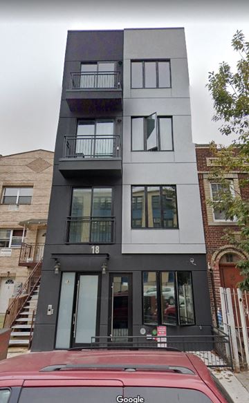Brooklyn apartment for rent - A red car is parked in front of a black and white building.