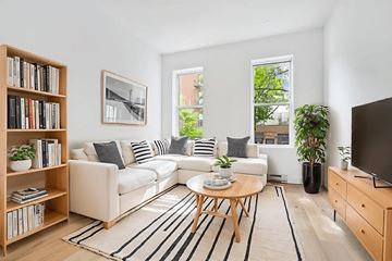 Brooklyn apartment for rent - A living room with a white couch, a coffee table, a bookshelf, and a television.