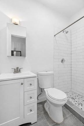 Brooklyn apartment for rent - A white bathroom with a toilet, sink, and shower.