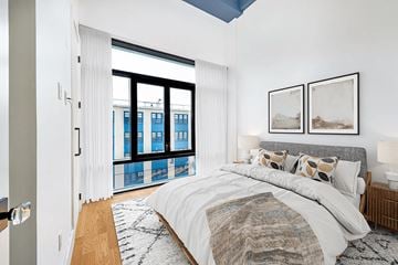 Brooklyn apartment for rent - A bedroom with a large bed and a view of a city skyline.