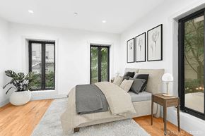 Brooklyn apartment for rent - A bedroom with a bed, a potted plant, and a table with a lamp.