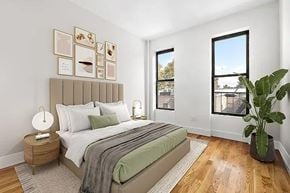 Brooklyn apartment for rent - A bedroom with a large bed and a potted plant.