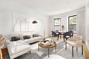 Brooklyn apartment for rent - A living room with a white sofa, a wooden table, and a lamp.