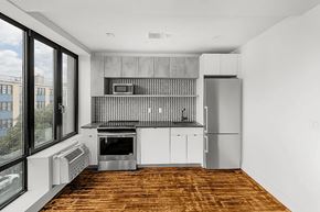 Brooklyn apartment for rent - A modern kitchen with a wooden floor and white walls.