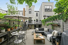 Brooklyn apartment for rent - A patio with a table and chairs is surrounded by plants and a building.