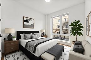 Brooklyn apartment for rent - A bedroom with a large bed, a couch, and a plant.