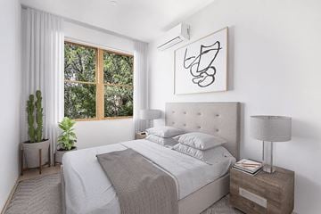 Brooklyn apartment for rent - A bedroom with a large bed, a nightstand with a lamp, and a window with a view of trees.