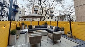 Brooklyn apartment for rent - A patio with a grey sofa and a wicker chair.