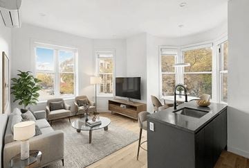 Brooklyn apartment for rent - A modern living room with a grey kitchen island and a large window.