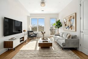 Brooklyn apartment for rent - A modern living room with a grey sofa, a wooden coffee table, and a large flat-screen TV mounted on the wall.