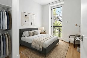 Brooklyn apartment for rent - A bedroom with a bed, a chair, and a window with a view of trees.