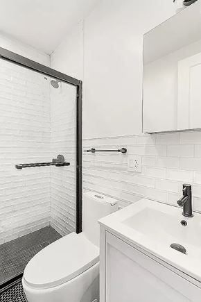 Brooklyn apartment for rent - A white toilet sits next to a white sink in a bathroom.