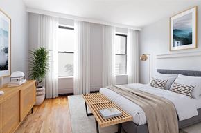 Brooklyn apartment for rent - A bedroom with a large bed, a wooden nightstand, and a plant.