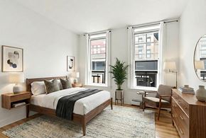 Brooklyn apartment for rent - A bedroom with a bed, chair, and a potted plant.