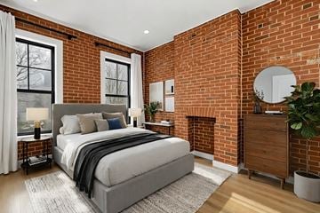 Brooklyn apartment for rent - A bedroom with a large bed and a brick wall.