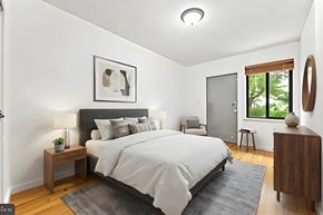 New York apartment for rent - A bedroom with a large bed, a nightstand, a chair, and a window.