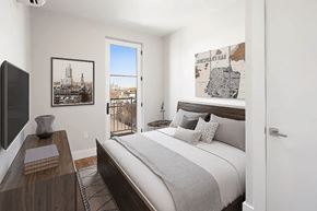 Brooklyn apartment for rent - A bedroom with a large bed and a balcony overlooking a city.