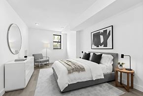 Brooklyn apartment for rent - A modern bedroom with a large bed, a chair, a dresser, and a mirror.