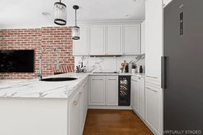 Brooklyn apartment for rent - A kitchen with a brick wall and white cabinets.