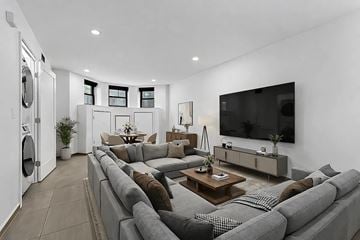 Brooklyn apartment for rent - A modern living room with a grey sofa set and a flat screen TV mounted on the wall.