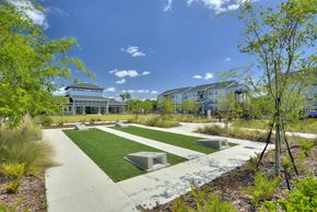 Lakeland apartment for rent - a park with benches and grass in front of a building
