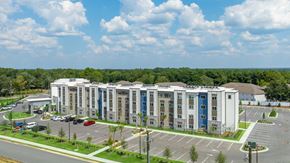 Crestview apartment for rent - A large multi-story building with a parking lot in front.