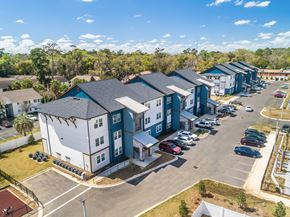 Tallahassee apartment for rent - an aerial view of a row of multifamily buildings with a parking lot and trees in the