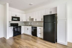 Crystal River apartment for rent - A black refrigerator stands in a kitchen with white cabinets.