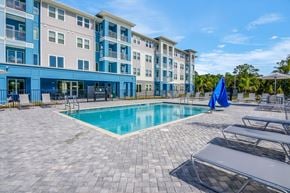 Crystal River apartment for rent - A large swimming pool is surrounded by a patio with lounge chairs and umbrellas.