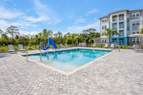 Crystal River apartment for rent - A swimming pool surrounded by a brick patio and a blue umbrella.