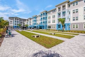 Crystal River apartment for rent - A sunny day at a modern apartment complex with a walkway and benches.