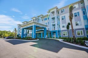 Crystal River apartment for rent - A large building with a blue and white exterior and a palm tree in front.