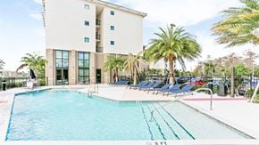 Margate apartment for rent - a large swimming pool with blue chairs and a building in the background