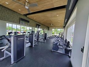 Miami apartment for rent - a gym with cardio machines and weights in a building with windows