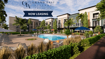 Orlando apartment for rent - A pool surrounded by chairs and plants is in front of a building that says Grand East Village.
