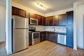 Holiday apartment for rent - A kitchen with dark wood cabinets and stainless steel appliances.