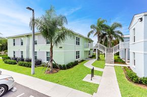 Belle Glade apartment for rent - a building with a staircase and palm trees in front of it