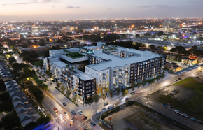 Miami apartment for rent - A modern building with a green roof is lit up at night with a cityscape in the background.